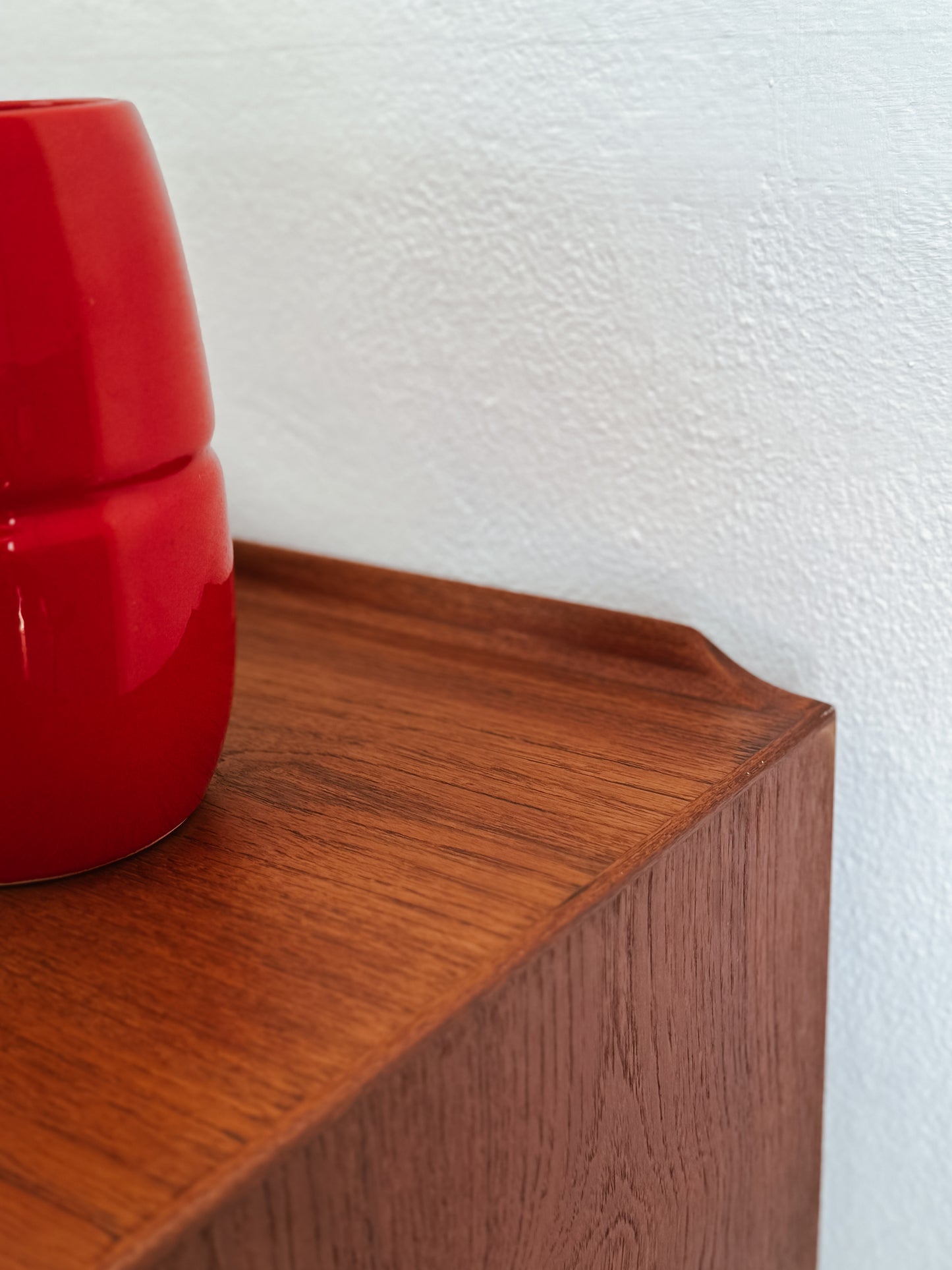 Credenza Arne Vodder in teak, dettaglio angolo piano superiore e bordo sagomato in teak vaso rosso