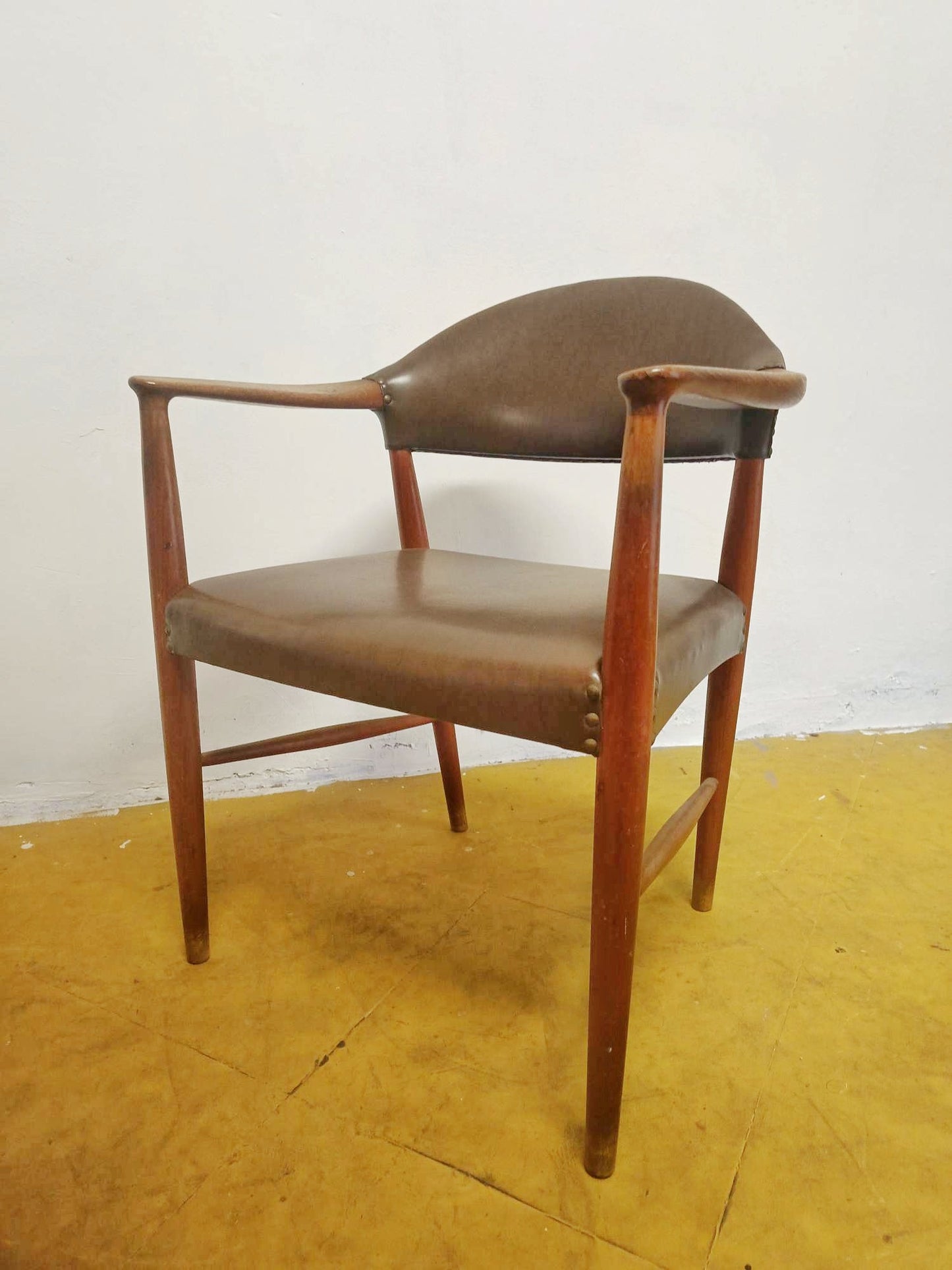 Poltroncina vintage danese Kurt Olsen anni 60 in teak, tre quarti destra, struttura a curve organiche e rivestimento in similpelle marrone