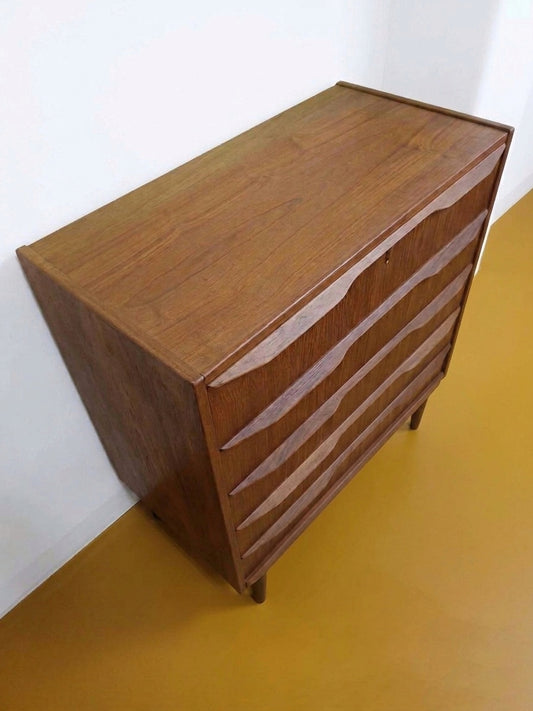 Cassettiera vintage danese anni 50 in teak, vista tre quarti, profilo verticale alto e maniglie a bow handle integrate nei frontali dei cassetti