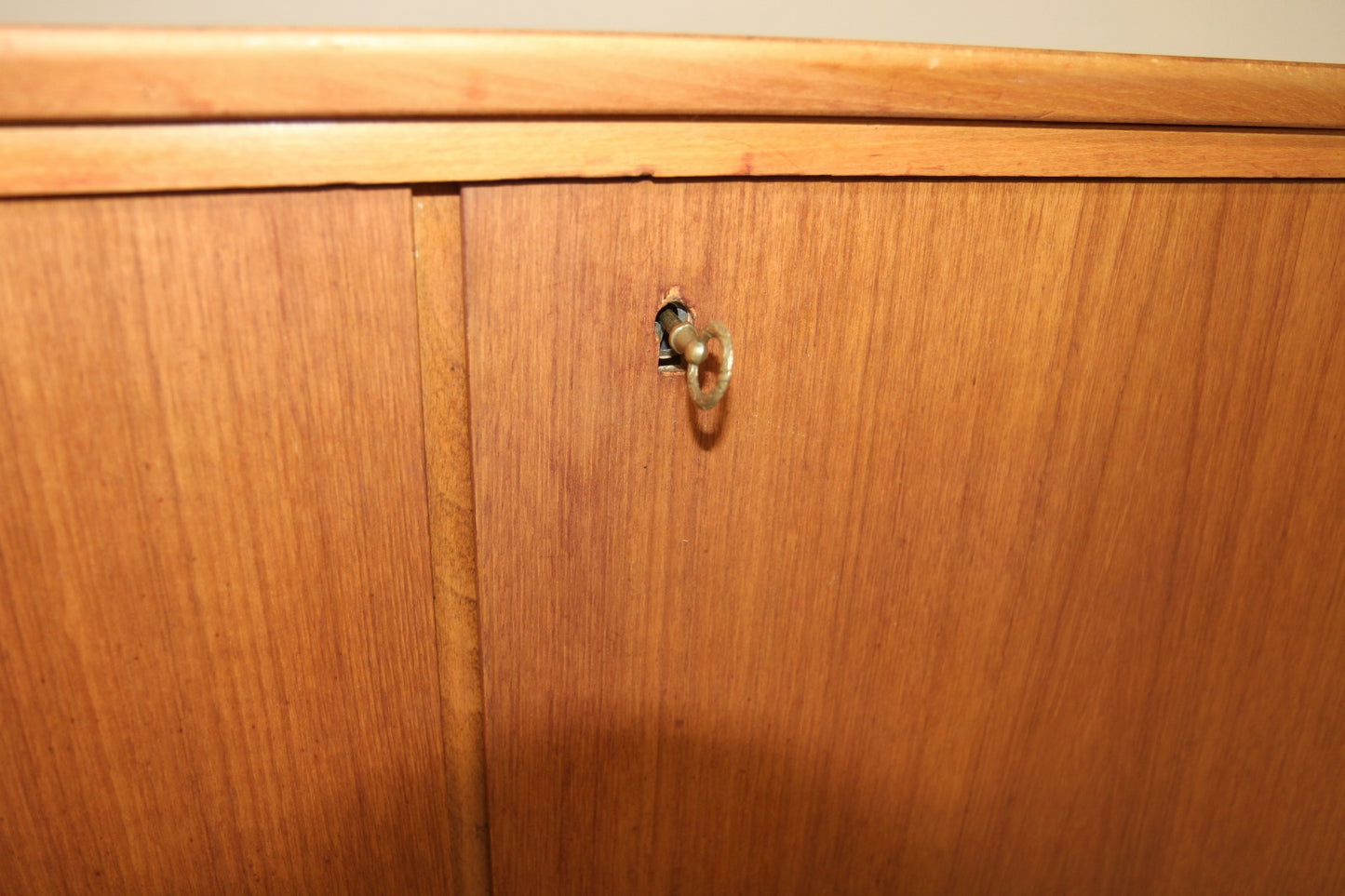 Close-up of a vintage wooden credenza door with a brass key in the lock.