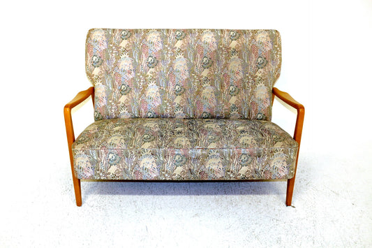 Vintage Scandinavian two-seater sofa with floral patterned upholstery and wooden arms.