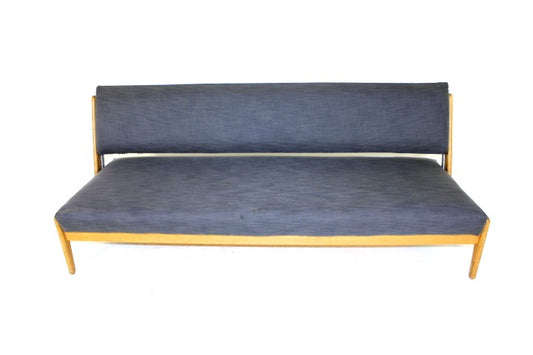 A vintage Danish daybed with a light wood frame and dark blue cushions.