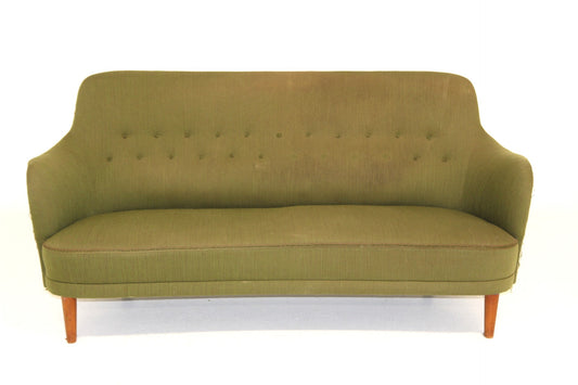 Olive green vintage sofa with button-tufted back and curved arms on wooden legs.