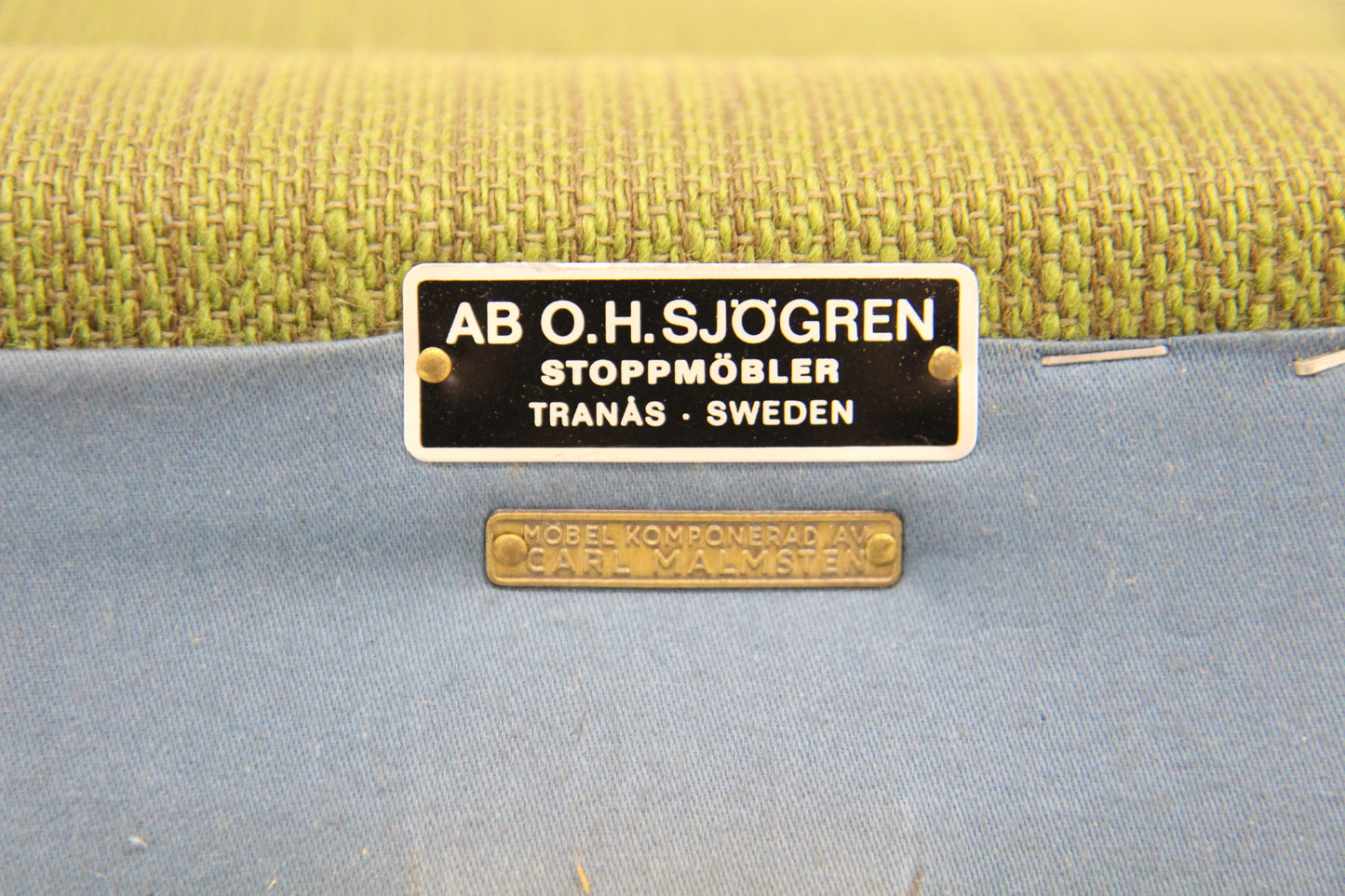 Vintage black and gold labels on green woven and blue plain upholstery fabric.