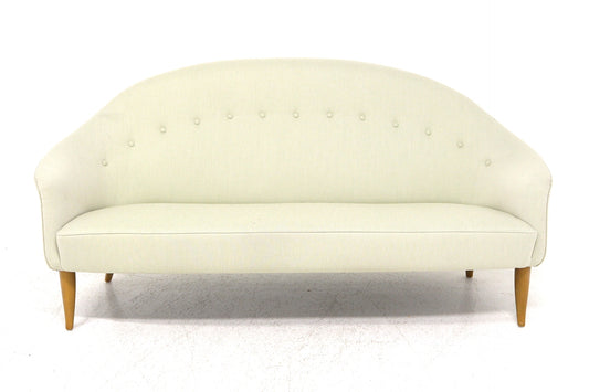 Light cream mid-century modern sofa with curved button-tufted back and wooden legs.
