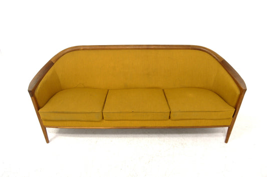 Mustard yellow fabric sofa with a curved wooden frame and three cushions.