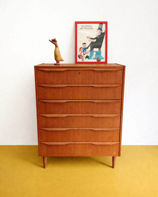Cassettiera danese anni 50 in teak, vista frontale, sei cassetti con maniglie ondulate intagliate nel frontale e gambe affusolate tornite