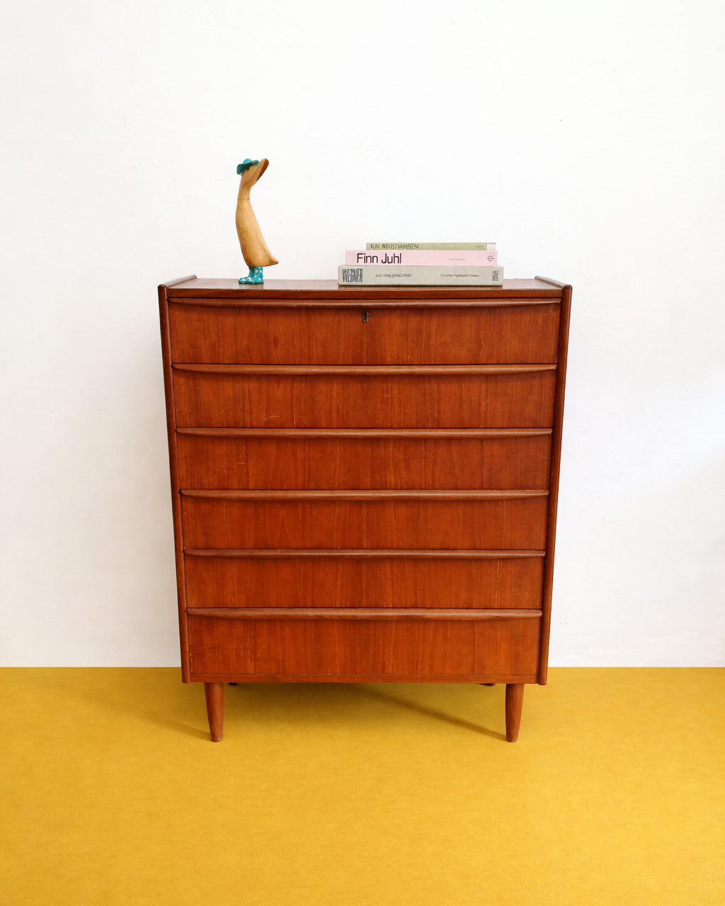 Cassettiera danese anni 50 in teak, vista frontale, sei cassetti con maniglie integrate a filo e gambe affusolate tornite