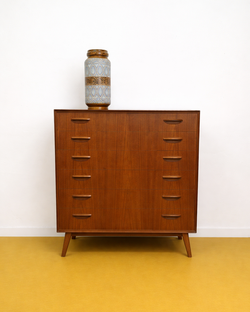 Cassettiera danese anni 50 in teak, vista frontale, sei cassetti con maniglie intagliate a V e gambe affusolate tornite