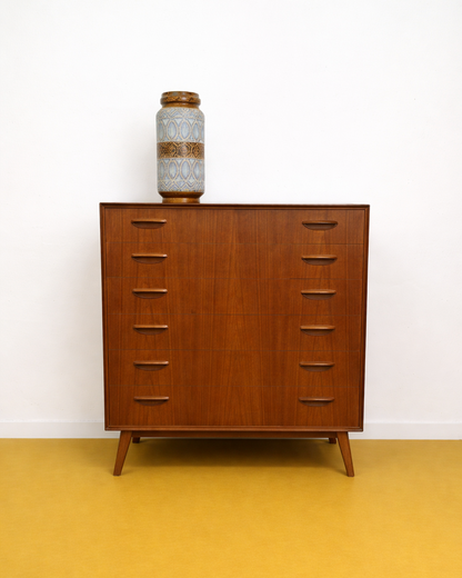 Cassettiera danese anni 50 in teak, vista frontale, sei cassetti con maniglie intagliate a V e gambe affusolate tornite