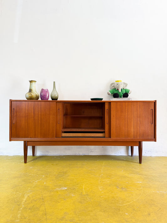 Sideboard danese vintage in teak anni 50 vista frontale con ante scorrevoli aperte, ceramiche e oggetti decorativi sul piano