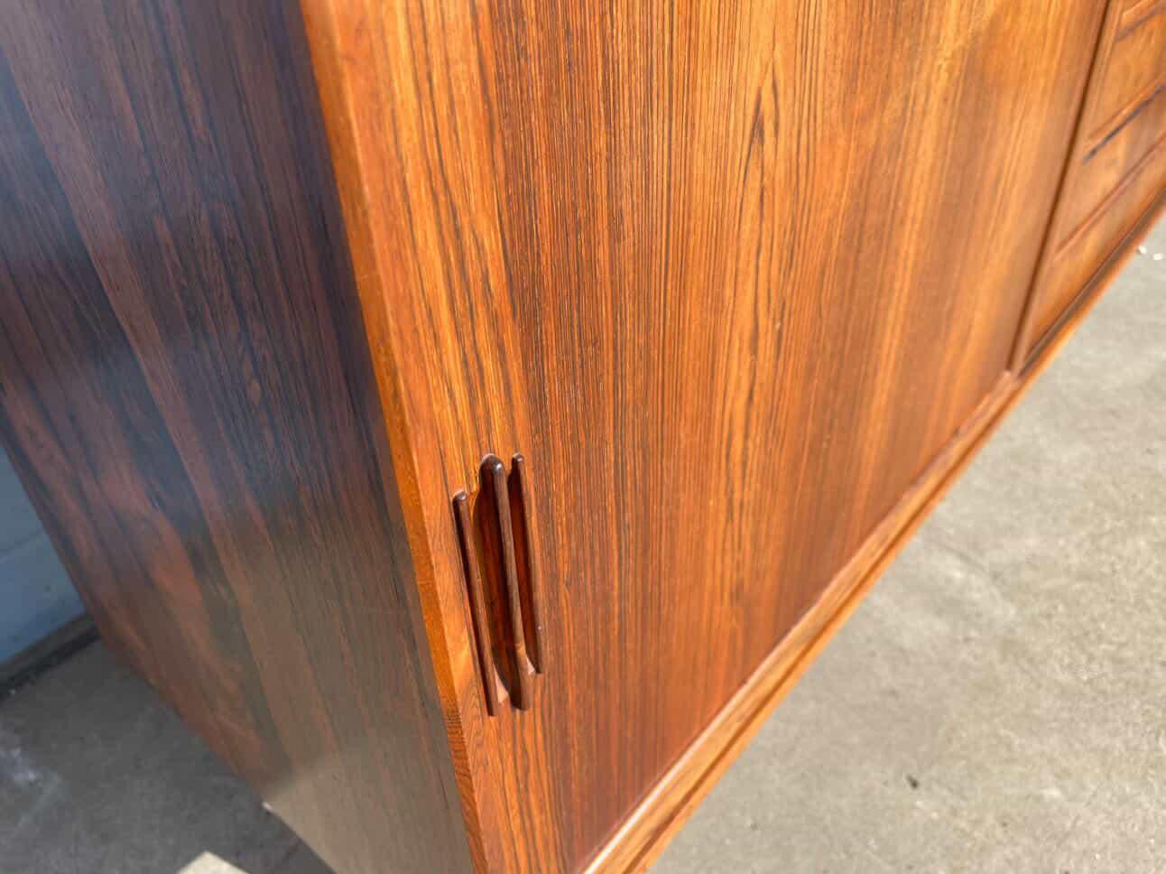 Dettaglio della maniglia verticale a incasso sull'anta scorrevole del sideboard danese