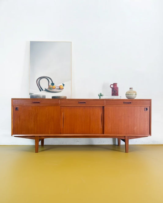 Sideboard danese in teak anni 50, fila di cassetti superiore e tre ante scorrevoli, gambe inclinate, ceramiche vintage sul piano, 200 cm