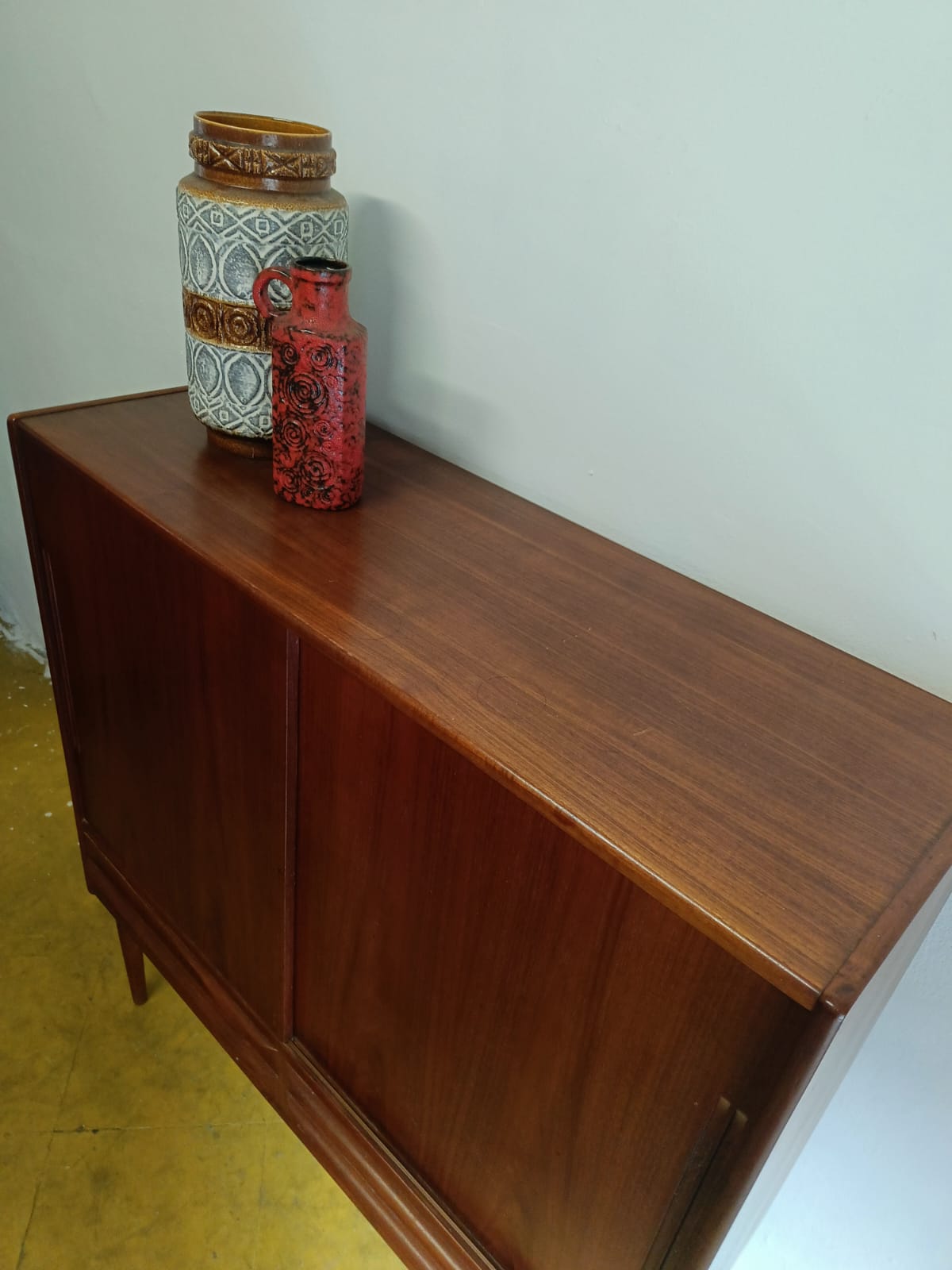 Armadio bar danese in teak anni 60, piano superiore con ceramica vintage e dettaglio bordo
