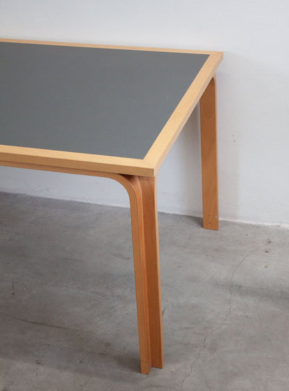 Dettaglio gambe curve e piano linoleum nero — tavolo vintage Magnus Olesen design danese