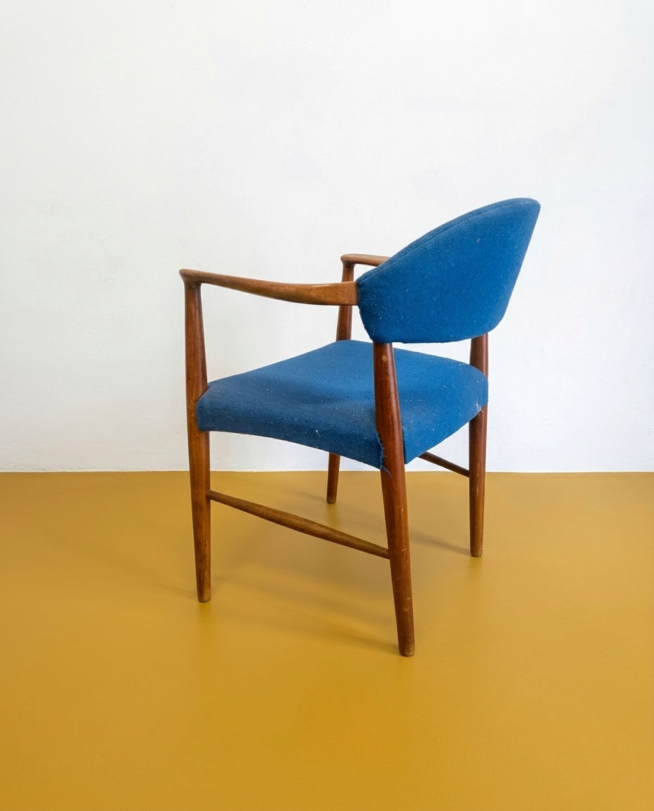 oltroncina Kurt Olsen danese anni 60 in teak, vista tre quarti, schienale a guscio curvato e braccioli integrati in teak, rivestimento in tessuto blu
