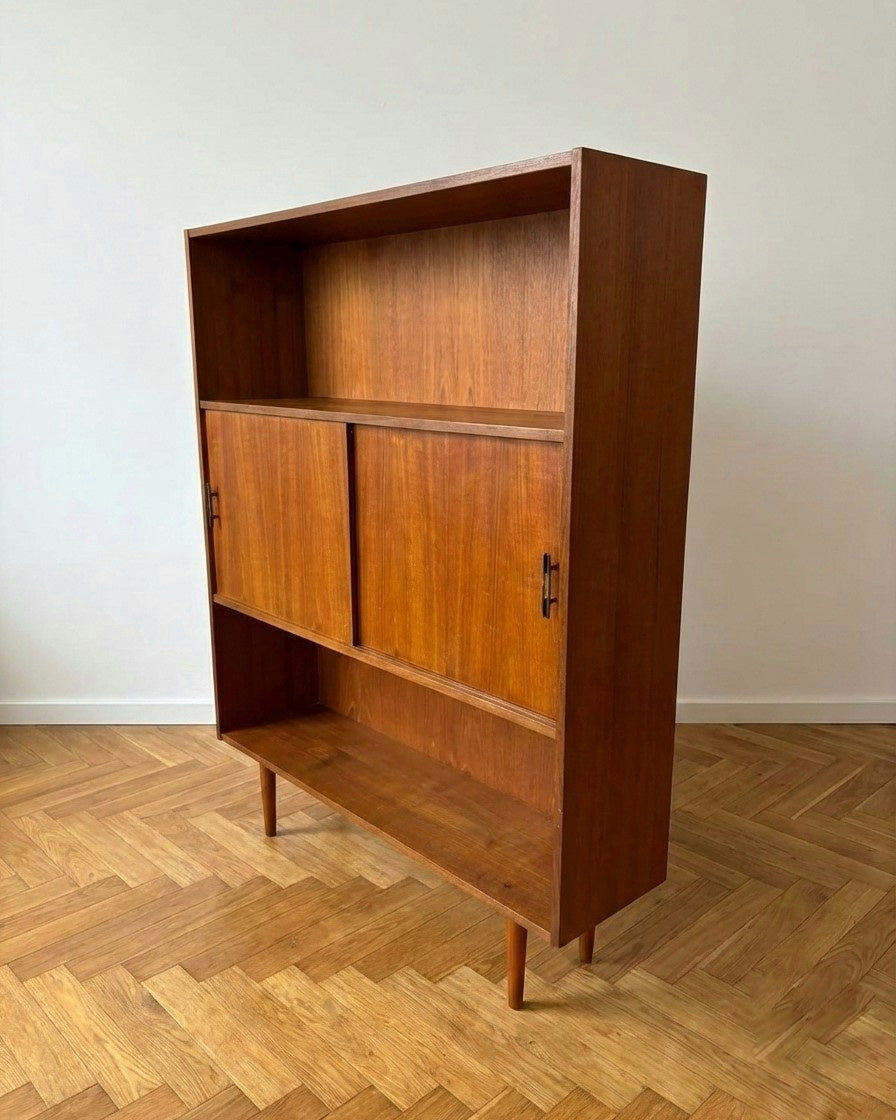 ibreria vintage danese teak anni 50, vista tre quarti frontale, vano centrale con ante scorrevoli in teak e gambe coniche affusolate