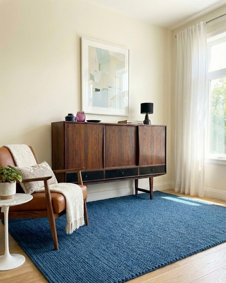 Credenza danese in palissandro anni 60, ante scorrevoli superiori e cassetti laccati nero, in soggiorno con poltrona in pelle e tappeto blu, 165 cm