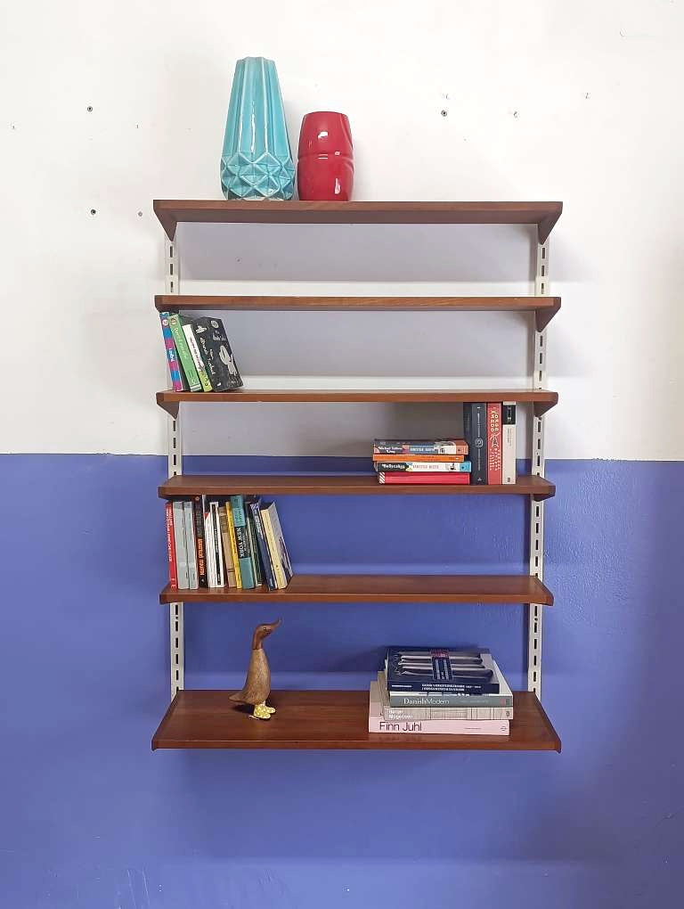 Vista frontale libreria Kristiansen composizione asimmetrica mensole teak montanti cremagliera bianchi